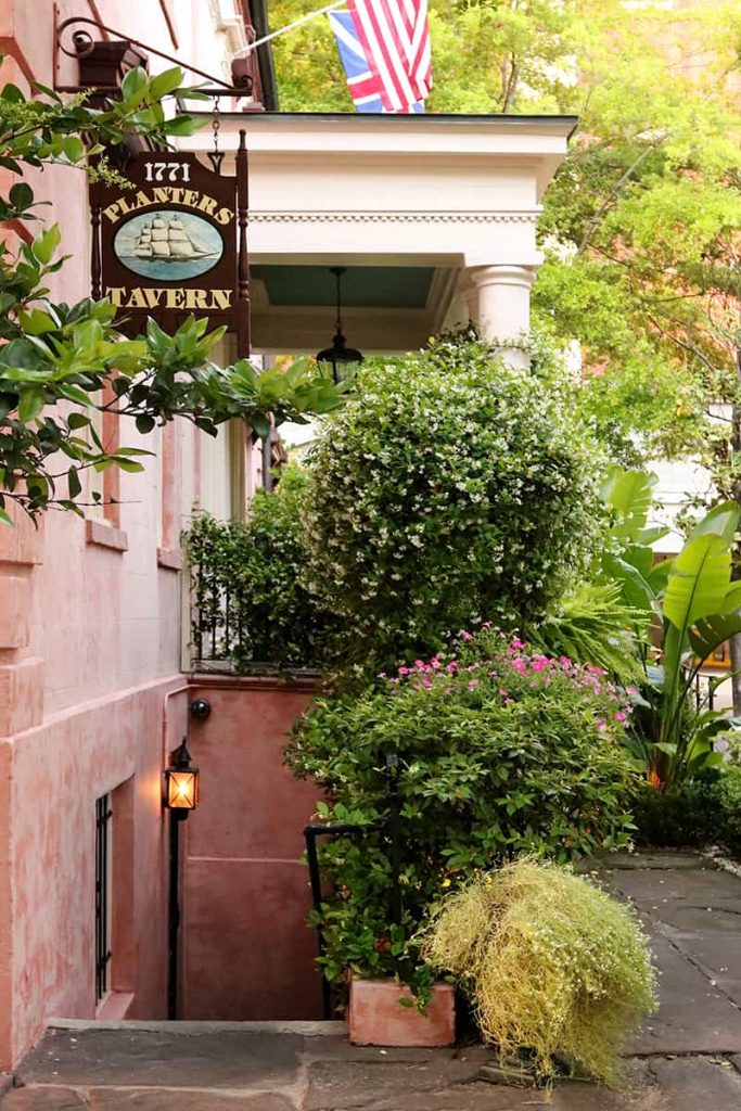 Pink stucco building with sign pointing down some stairs to a basement-level tavern