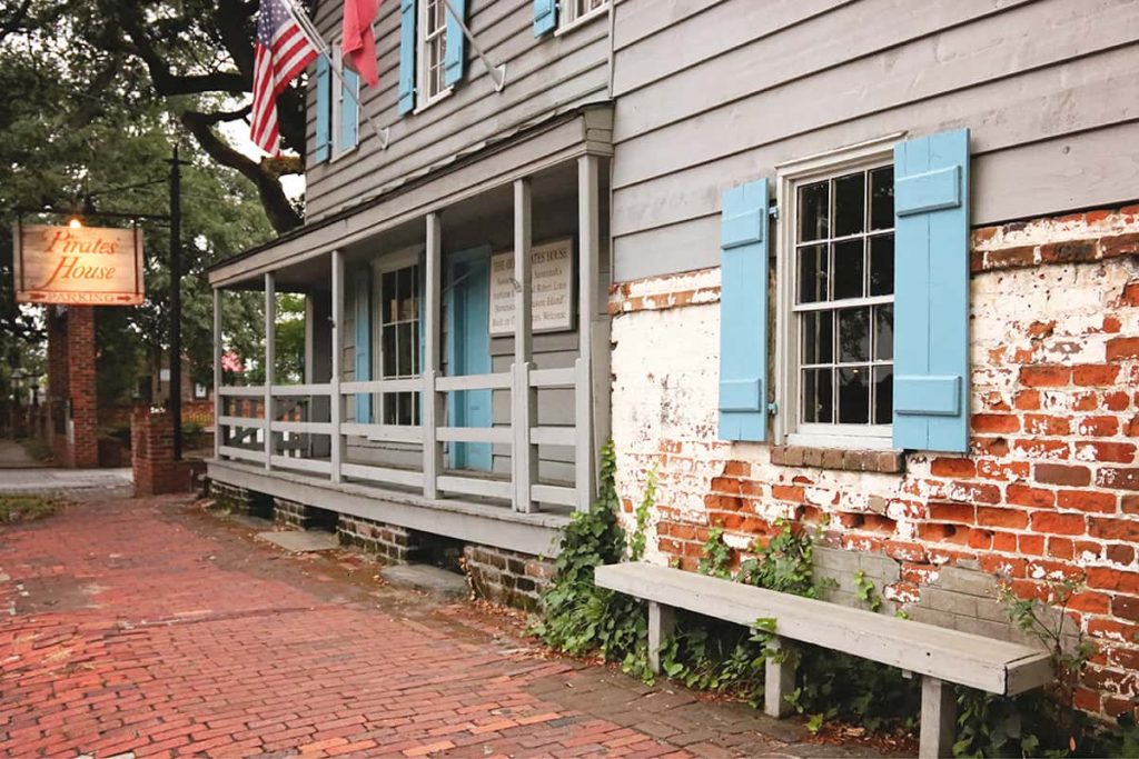 Old wooden building with blue shutters and exposed red bricks