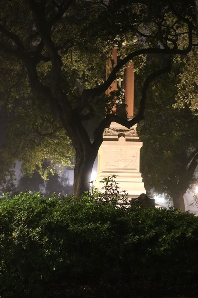 Oak trees and a large monument at night shrouded in mist