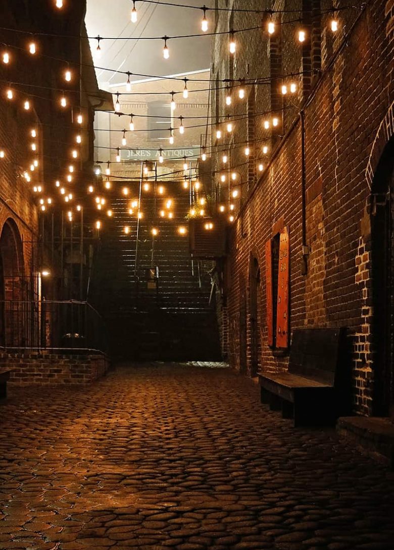 Dimly lit alley at night with stairs leading to mist in the background