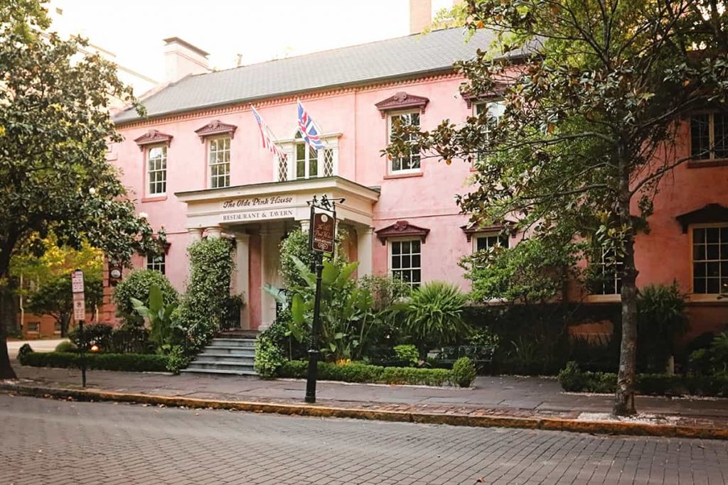 Estately two-story pink stucco home with flags displayed over the front portico