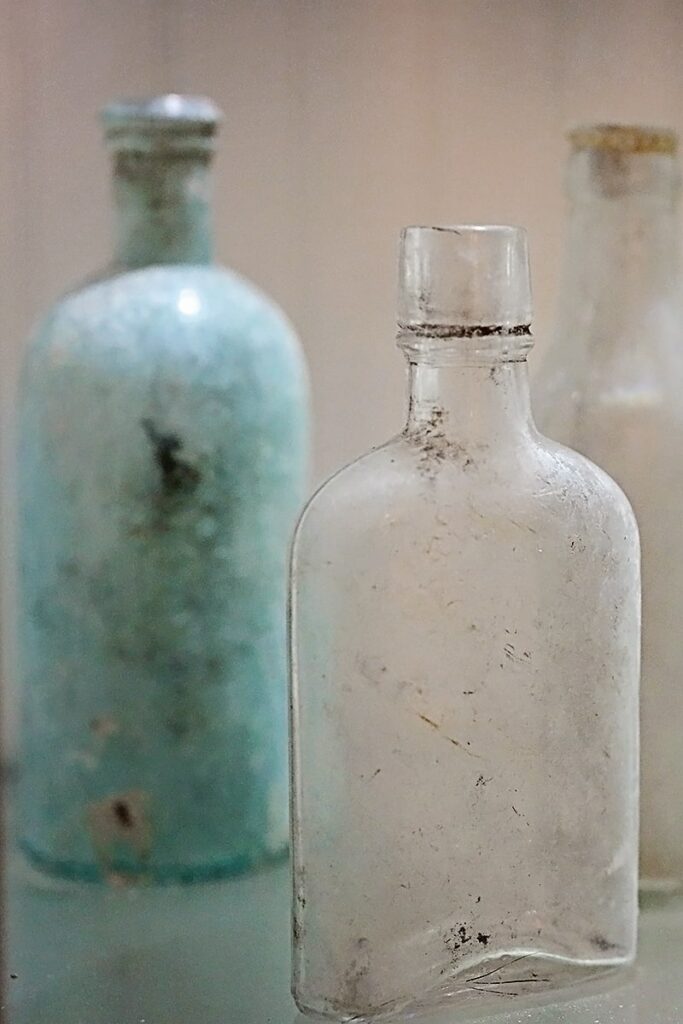 Vintage glass bottles displayed on a lighted shelf inside The Marshall House