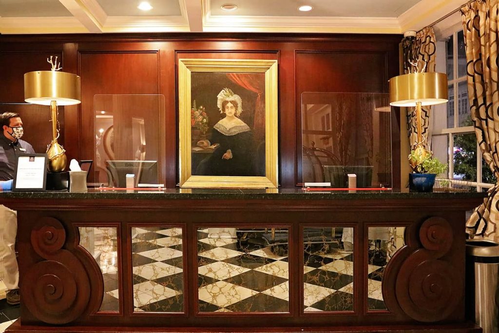 Mahogany check-in desk at The Marshall House with a painted portrait of Mary Marshall in a gold frame above the desk