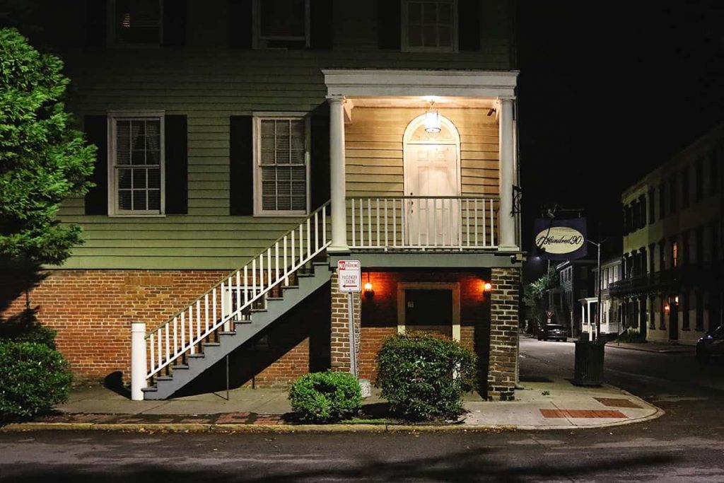 Entrance to the 17Hundred90 Inn with a brown brick first floor and green wooden upper floors with black shutters