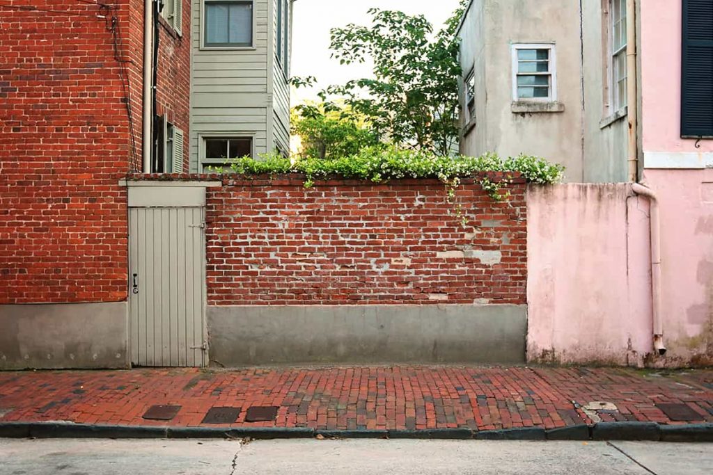 Pink house and red brick wall with Confederate Jasmine spilling over the top from a secret garden in Savannah's Historic District