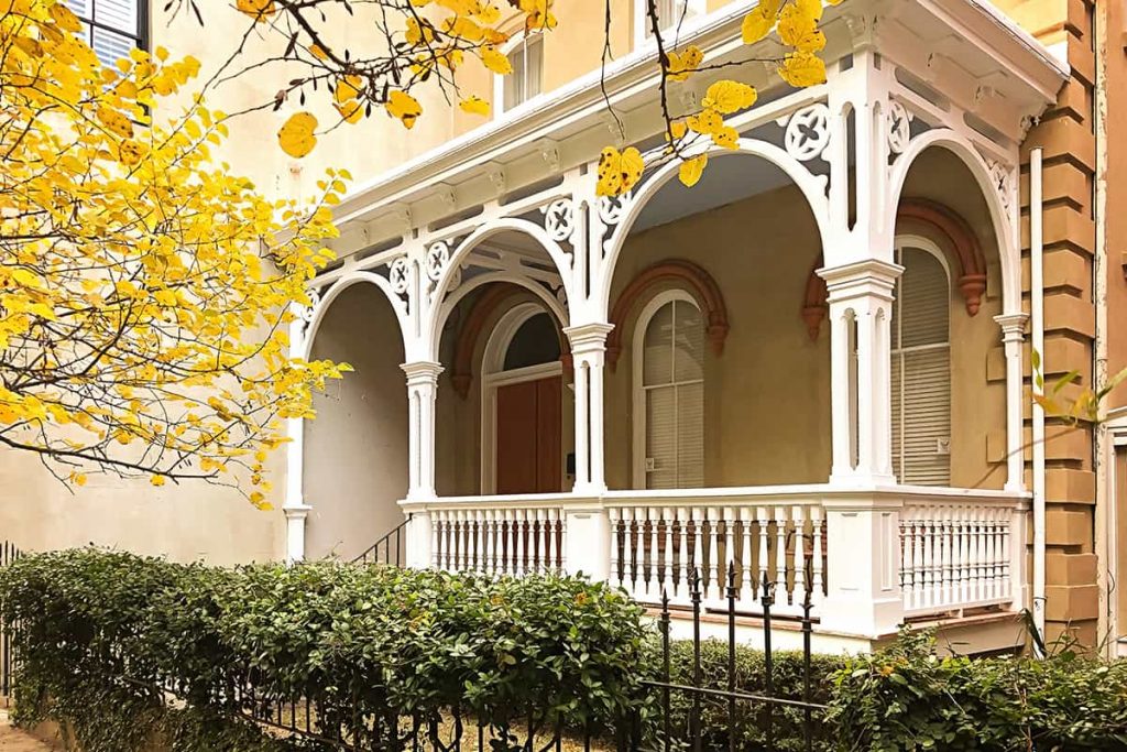 Yellow leaves surrounding an intricate Victorian porch on a home in Savannah