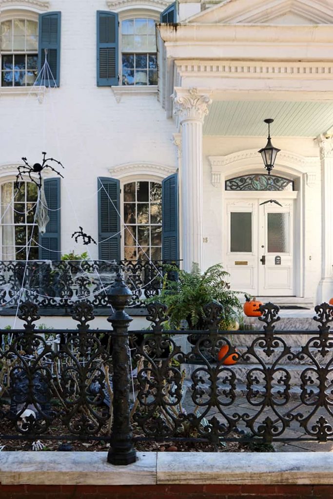 Multi-story mansion with pumpkins and fall decorations on the front porch