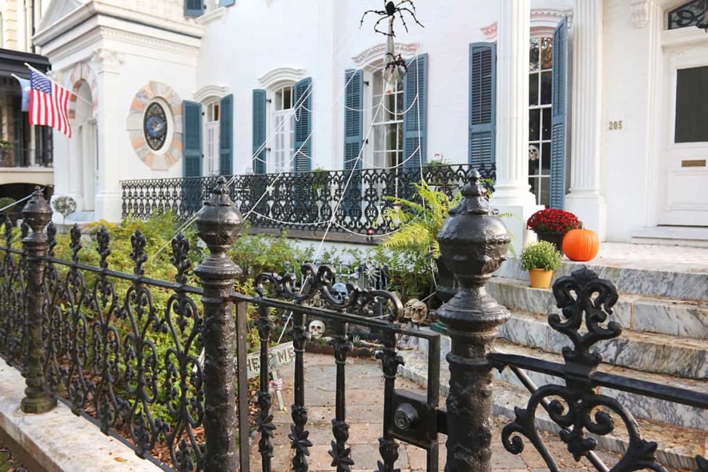 Multi-story white mansion in Savannah with a giant spiderweb and spooky Halloween decor