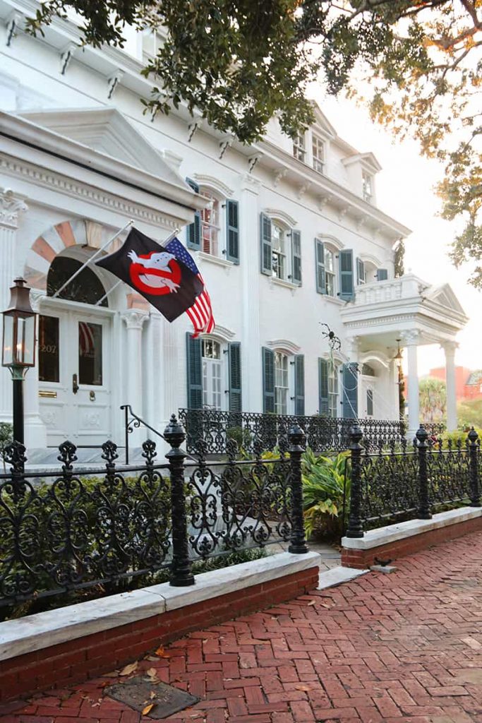 Multi-story white mansion with a Ghostbusters flag hanging over the front door