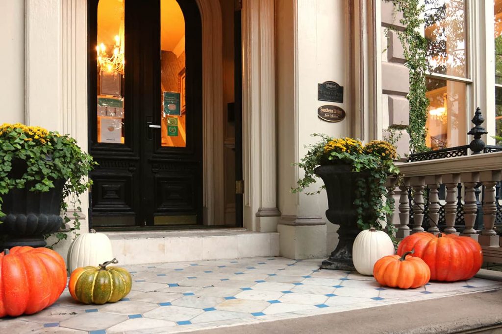 Front porch of an elegant mansion decorated with pumpkins and fall decor