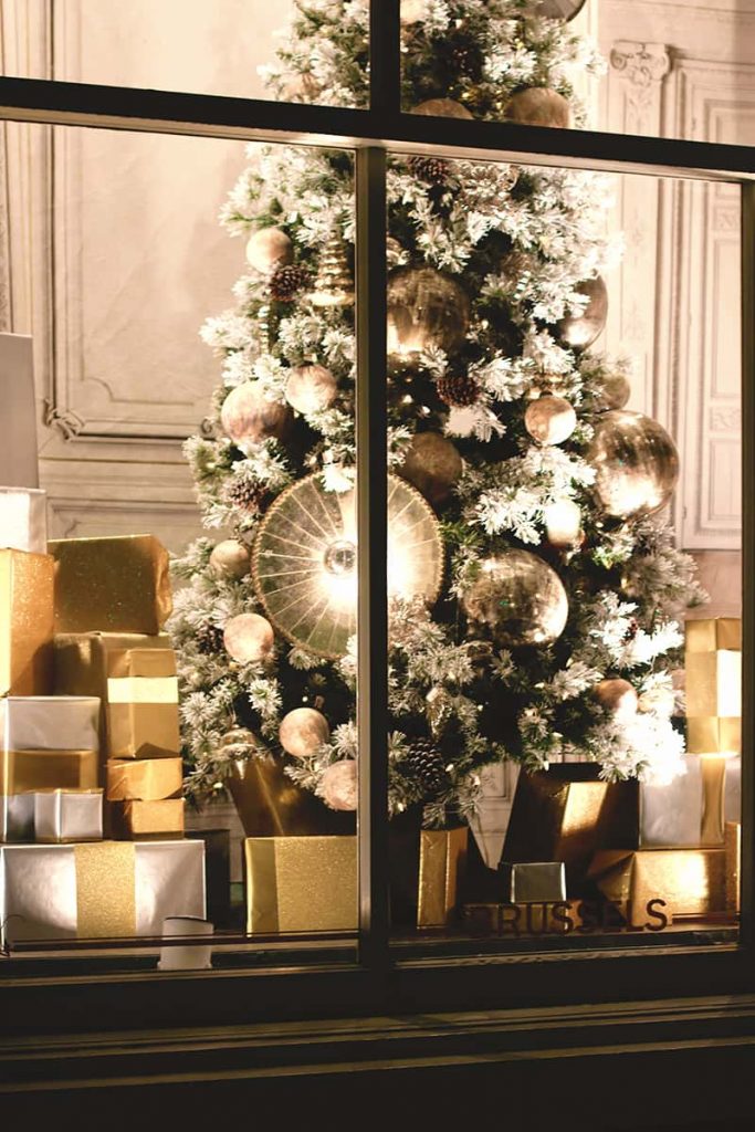 Vitrine élégante montrant un sapin de Noël avec des décorations dorées et blanches