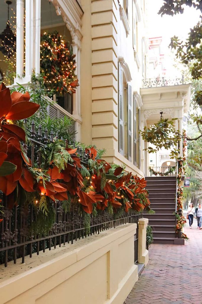 Nahaufnahme eines Magnolienblatts Swag drapiert auf dem schmiedeeisernen Tor eines historischen Hauses in Savannah