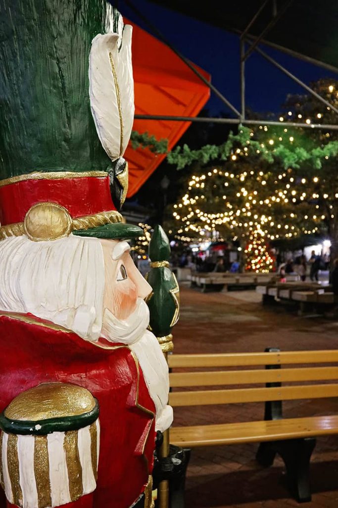 View of the Christmas lights in Savannah's City Market, as seen over the shoulder of a life-sized nutcracker