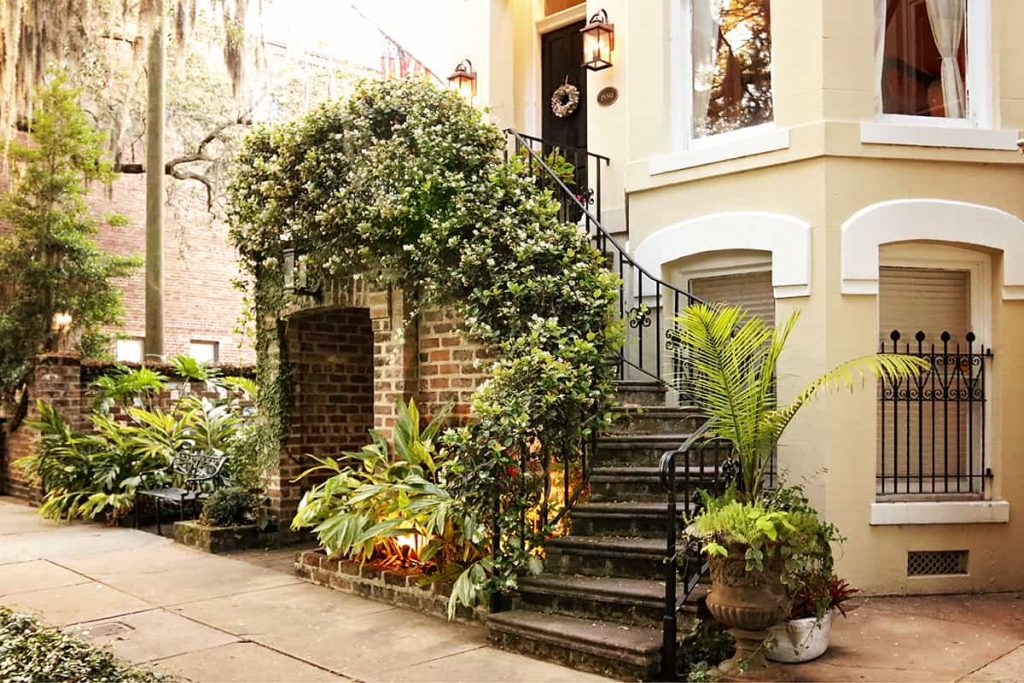 Container plants and climbing Confederate Jasmine surround the entry to a home on Jones Street