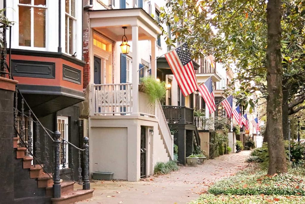 Jones Street sidewalk view of a row of homes each with an American flag hanging from the porch