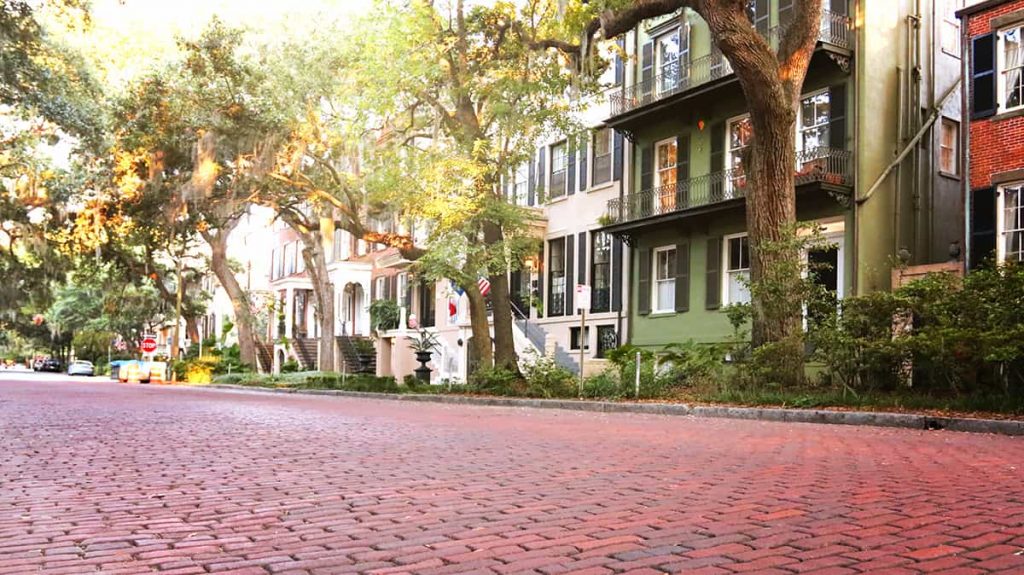 Jones Street, the prettiest street in America, with a wide expanse of brick pavers in the foreground and large homes and mature oaks in the background.