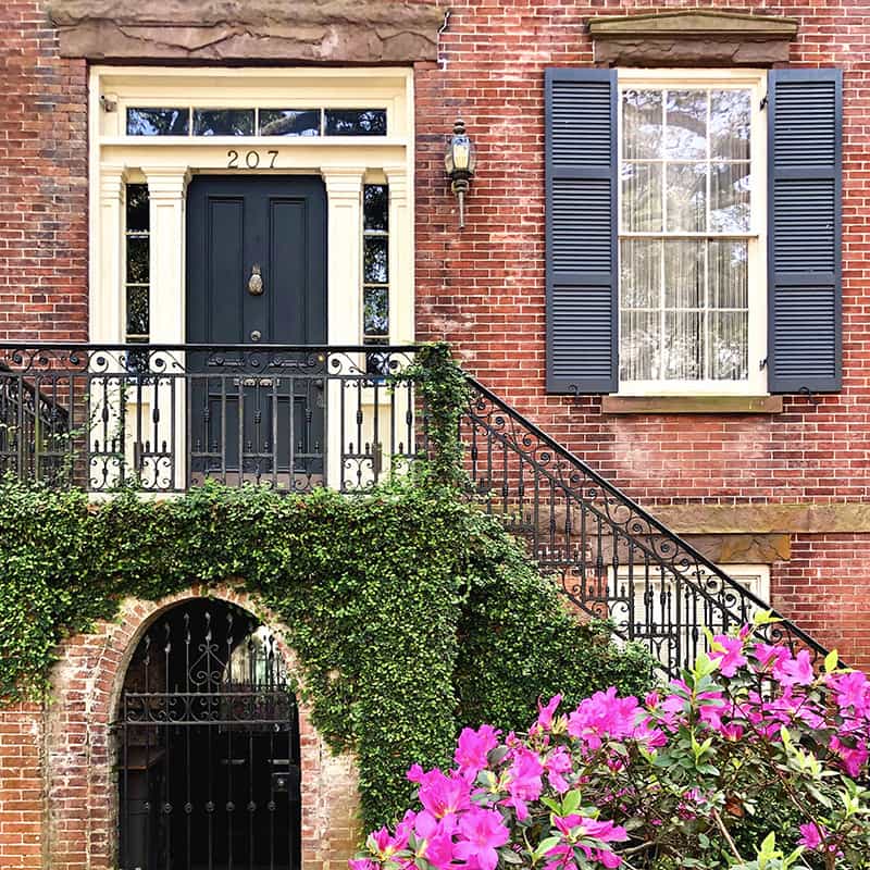 Historic brick home facade on Jones Street with hot pink azaleas blooming in the foreground