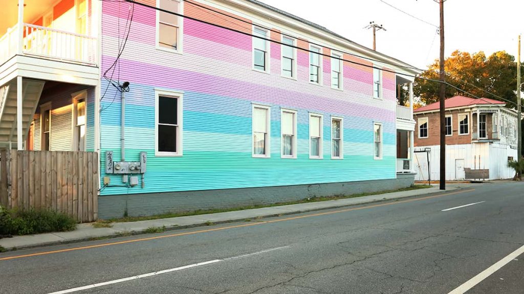 Side view of a large 2-story home with rainbow stripes painted down the entire length of the building
