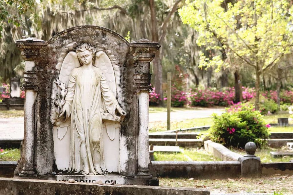 Worn headstone of an angel with a detached look on her face