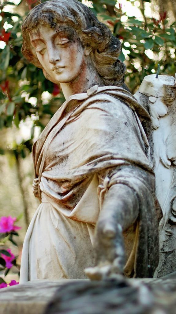 Close-up of a statue of an angel with her hand outstretched and stains that look like red tears dripping down her face
