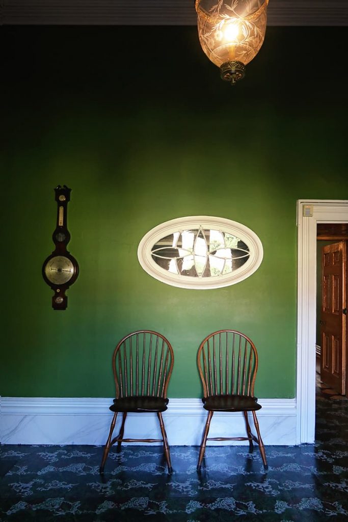 An elegant room with deep green painted walls, marble trim, and leaded glass decor