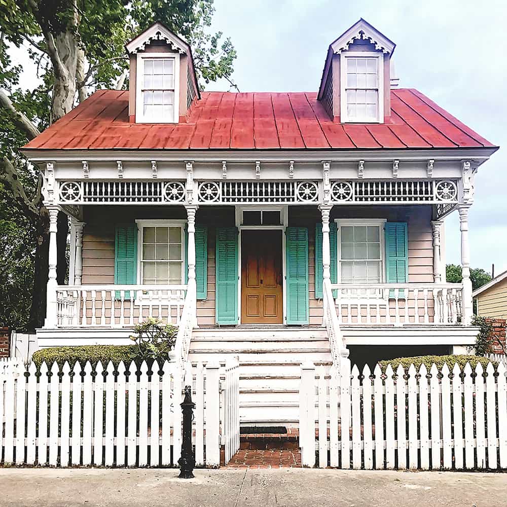 Exterior of the King Tisdell Cottage with a red metal roof, haint blue shutters, and Victorian-style trim