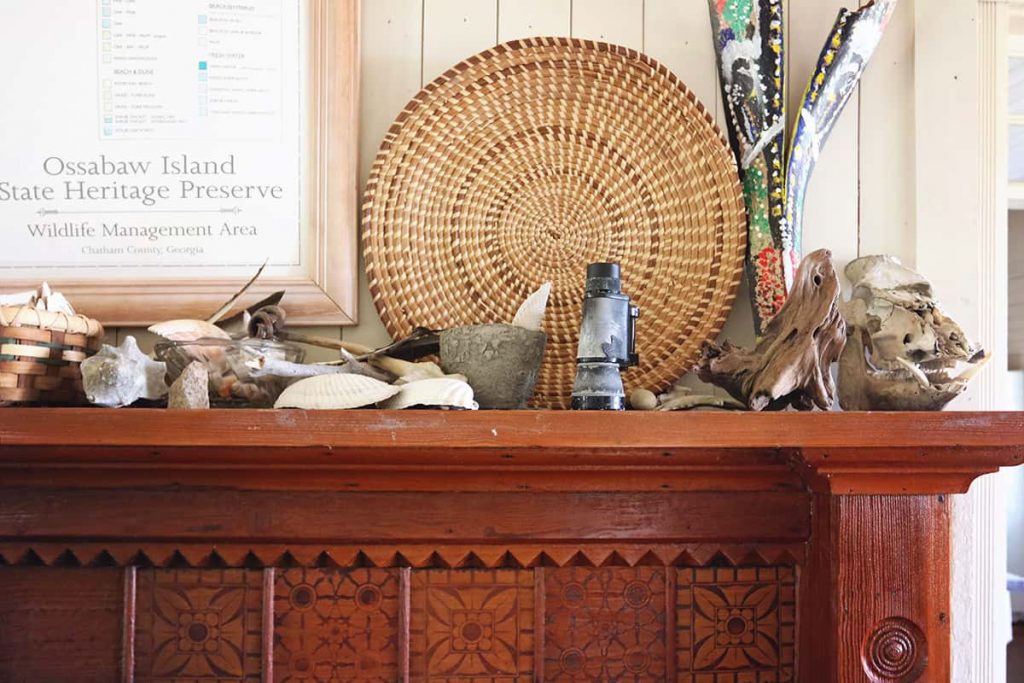 Beautiful carved wooden bookshelf with a woven grass basket and seashells perched on the mantel