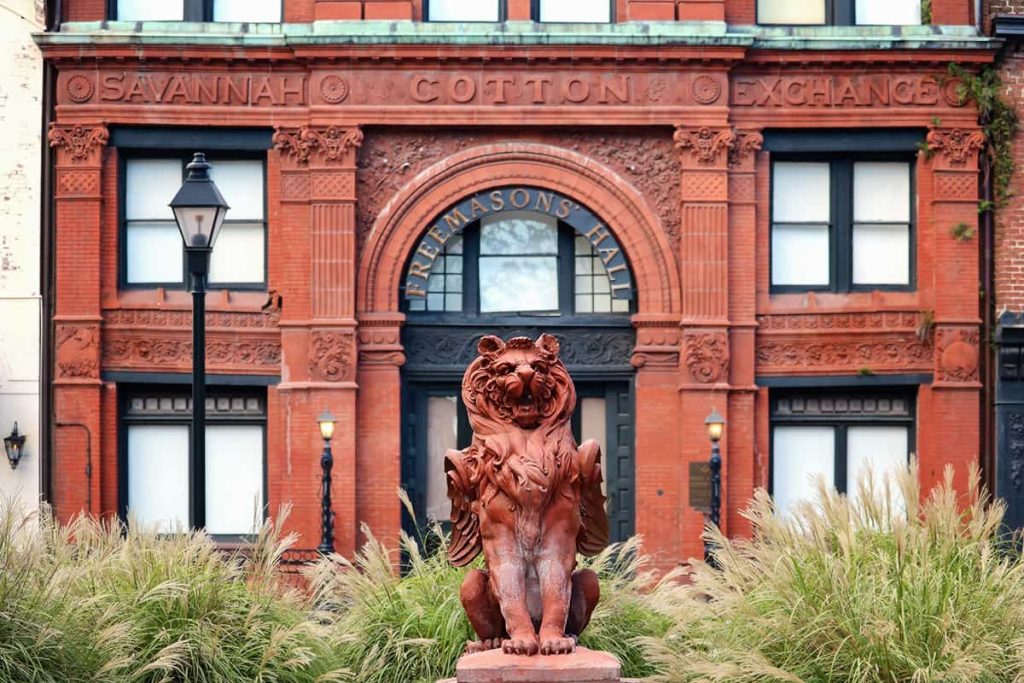 A terra cotta winged lion statue stands guard in front of the Old Savannah Cotton Exchange building