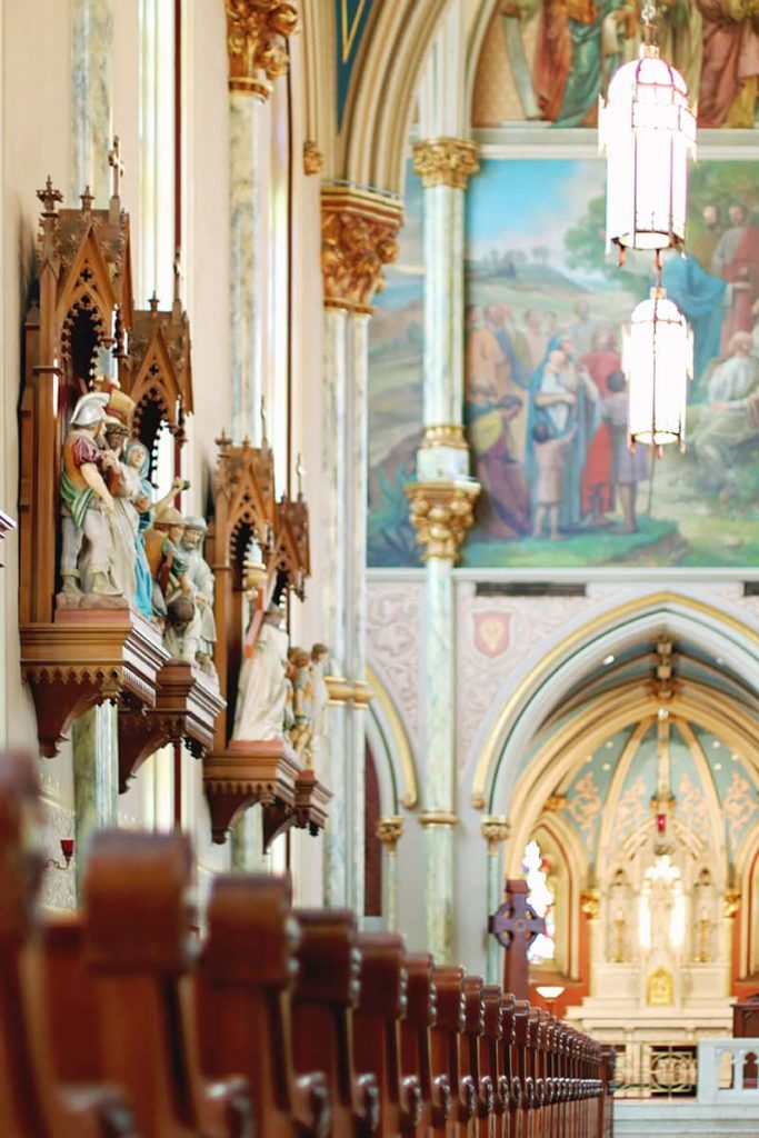 Elaborately carved Stations of the Cross hang on a wall above the pews at the Cathedral Basilica of St. John the Baptist in Savannah, GA