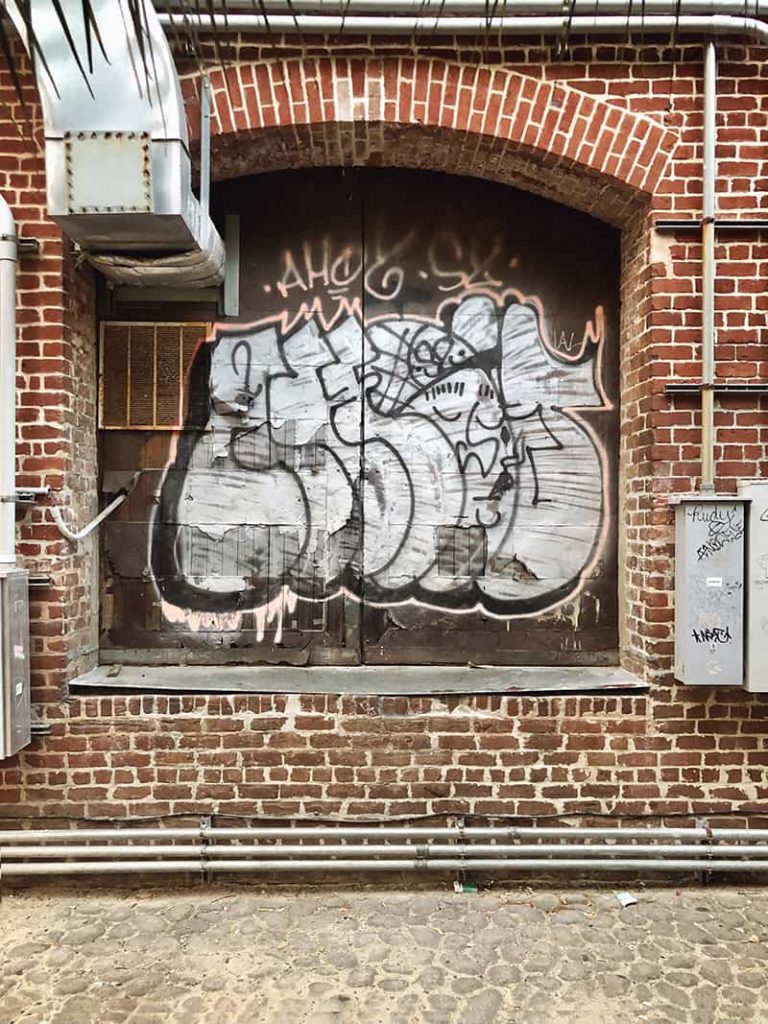 Old bricks surround a boarded window with graffiti sprayed on the wood along Factors Walk in Savannah