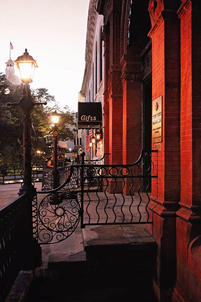 Dusk scene of the Old Cotton Exchange Building on Factors Walk in Savannah with red bricks aglow from historic gas lanterns