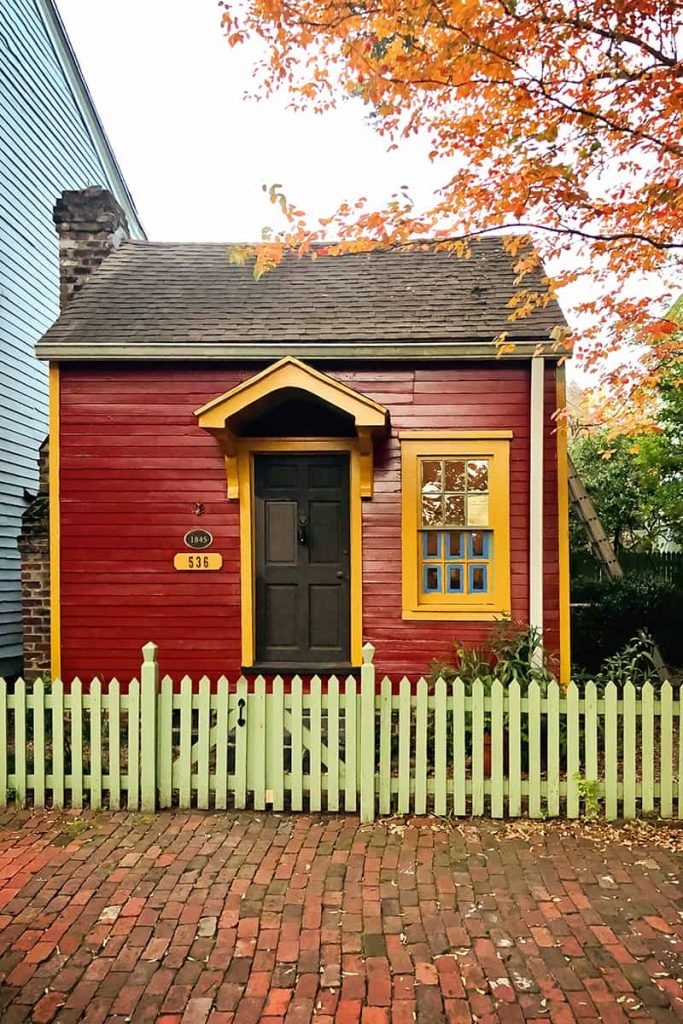 The smallest house in Savannah is painted red with yellow trim and has an historic brick sidewalk in front of it