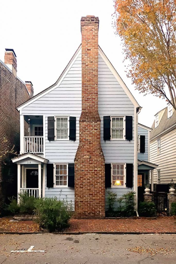 Two-story blue home with a chimney as the focal point and a steeply pitched roof