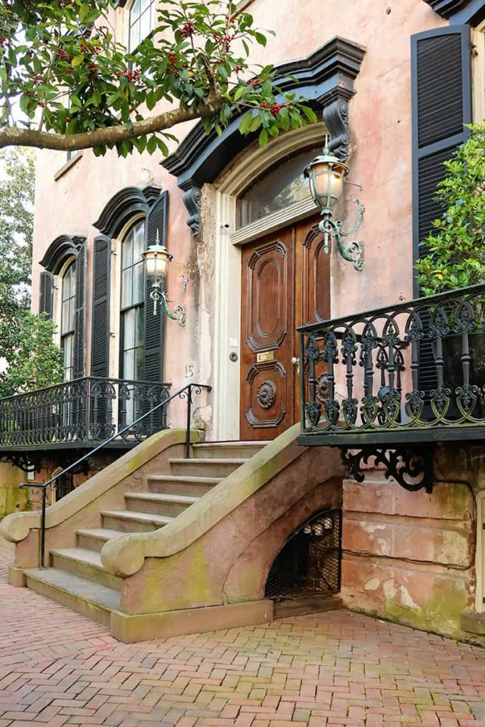 Elaborate front entry in the Savannah Historic District with carved wooden doors, gas lanterns on each side, and historic brick sidewalks