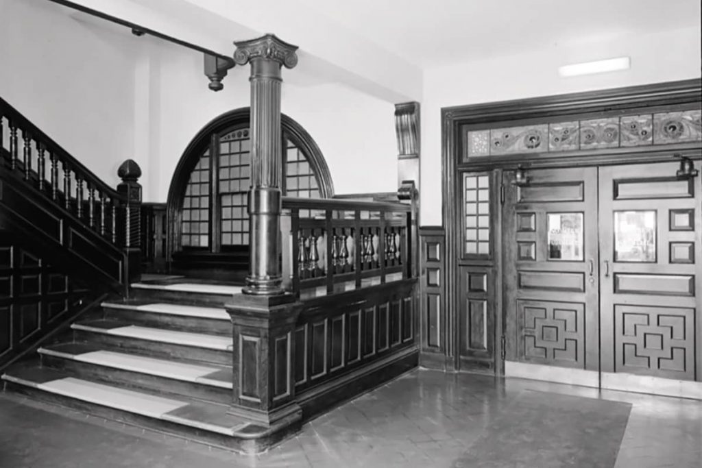 A wide stairwell and oversized doors with stained glass above in the interior of the old Savannah Cotton Exchange building on Factors Walk