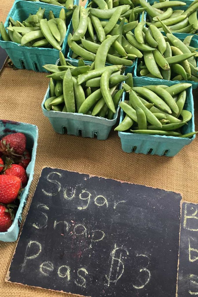 Small blue baskets of fresh sugar snap peas at the Forsyth Farmers' Market