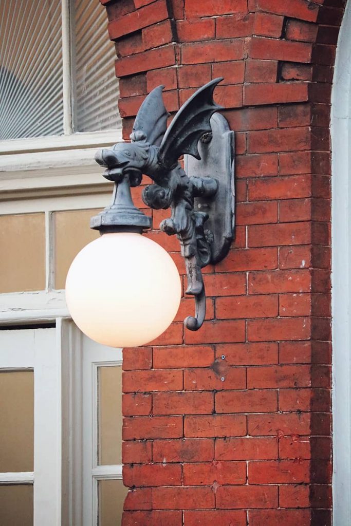 A gargoyle light fixture hangs from beside an arched brick door along Factors Walk