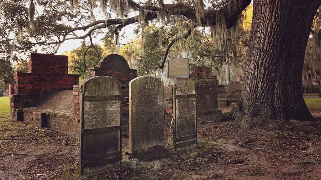 A trio of headstones beneath an old oak covered in Spanish moss in Colonial Park Cemetery