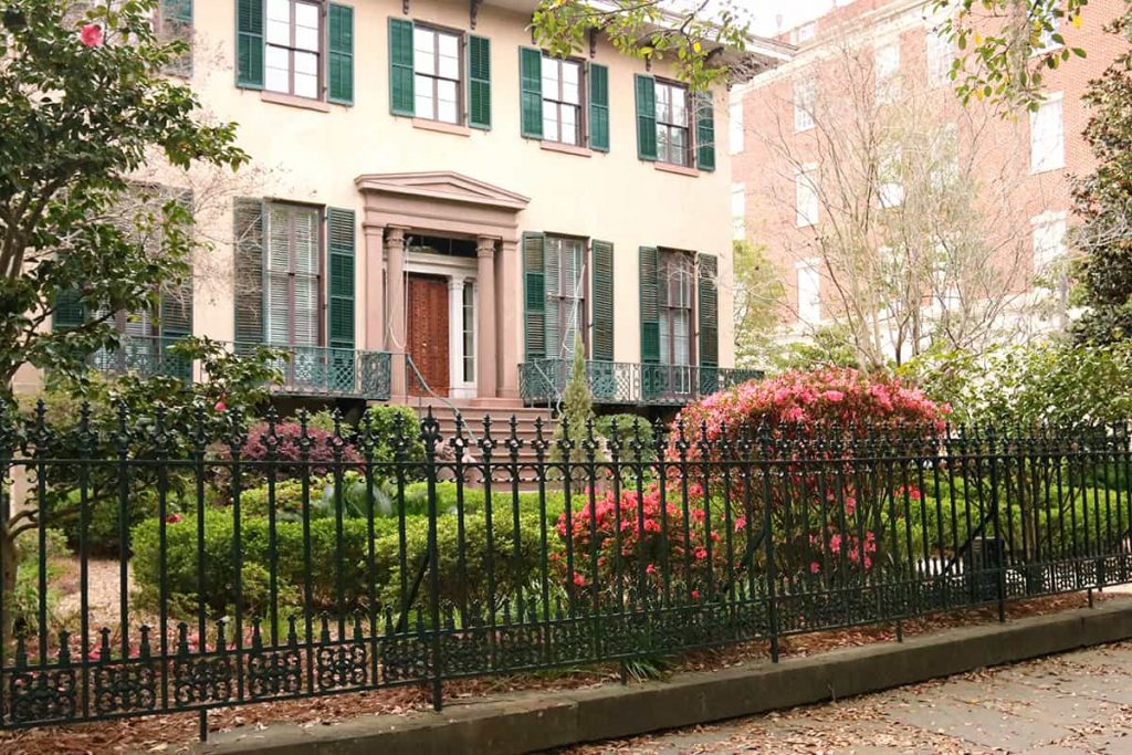 The two-story Andrew Low House with green shutters and lush landscaping behind an iron fence