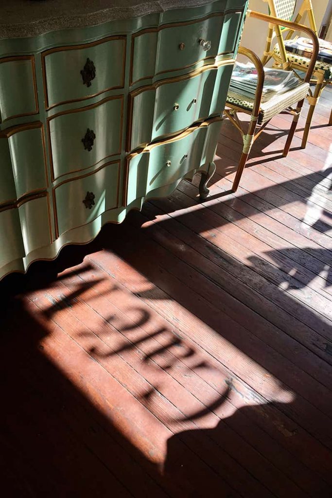 Sunlight streaming through a window causing a silhouetted shadow of the Café M sign in Savannah