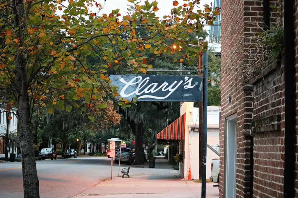 A charming old-timey B&W sign for Clary's Cafe surrounded by trees with fall color