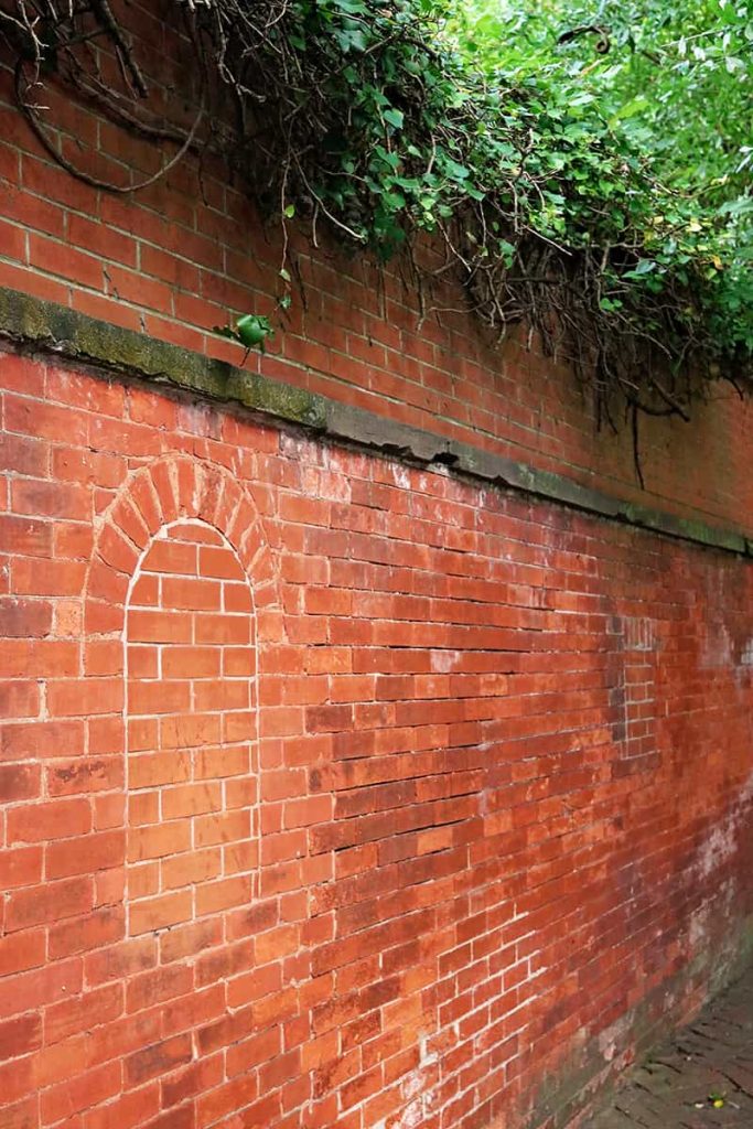 Historic red brick wall with the faint outline of a window that has been bricked over