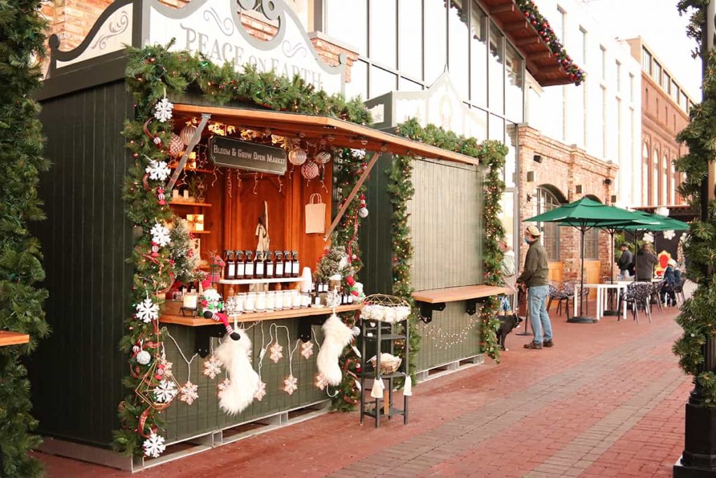 A Christmas booth filled with aromatherapy bottles and decorated with greenery and fuzzy white Christmas stockings