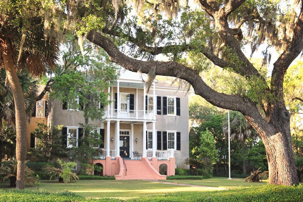 Stately brown tabby manse surrounded by lush landscaping and oaks in the Lowcountry of South Carolina