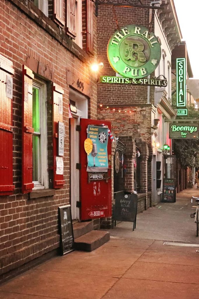 Evening street scene of bar entrances and neon signs in Savannah's Historic District