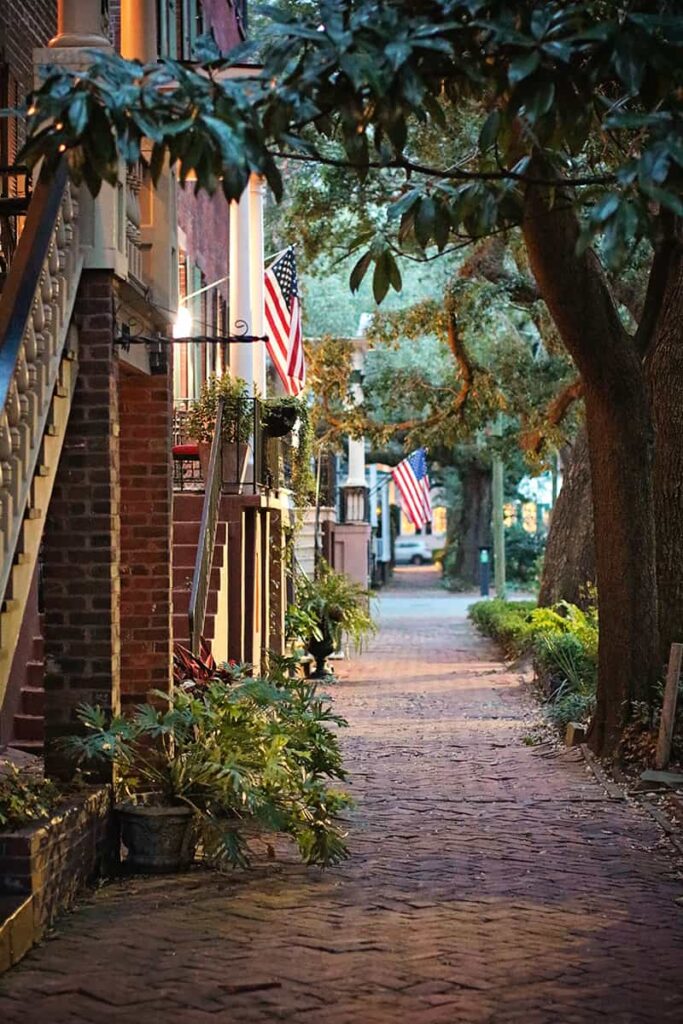 Picturesque sidewalk scene of Jones Street, the prettiest street in Savannah, with brick sidewalks, magnolia trees, and stately homes