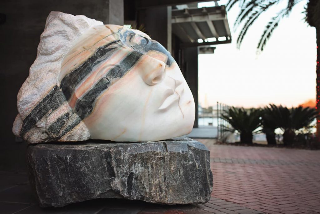 Large face sculpture carved out of a chunk of white and black stone