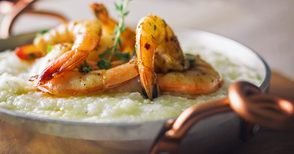 Close-up of a savory bowl of shrimp and grits with a sprig of green garnish