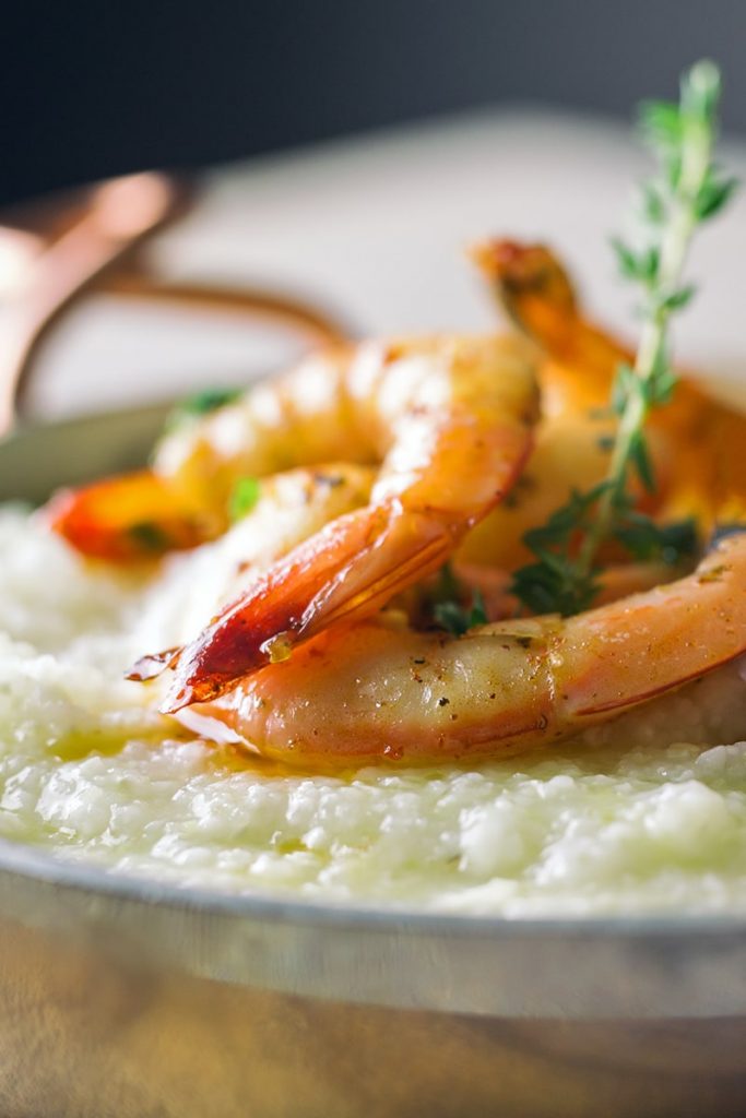 Close-up of the best seafood in Savannah, a savory bowl of shrimp and grits with a sprig of green garnish