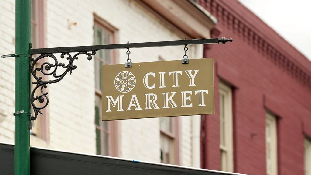 City Market sign with red and white-painted brick warehouses in the background